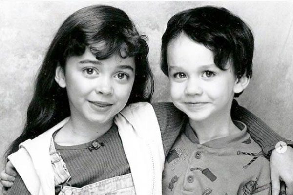 Black and white photo of Ian Hyland in a buttoned t-shirt with his sister in a sweater and dungaree.
